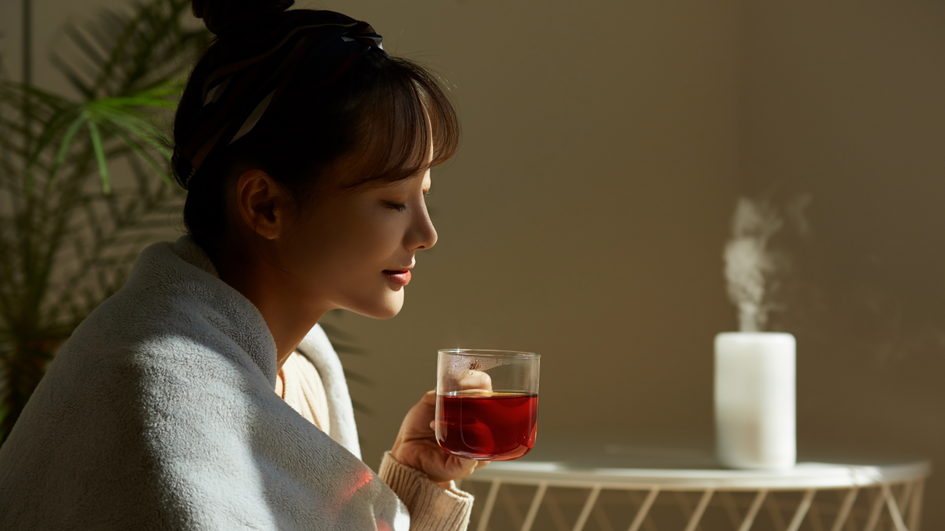 ハーブティーを口もとへ運ぶ女性